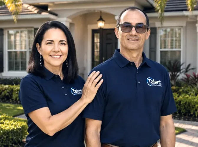 Karla Paiva e John Vicente, os donos da Talent Cleaning Services, juntos e de uniforme em frente a uma casa no sul da Florida.
